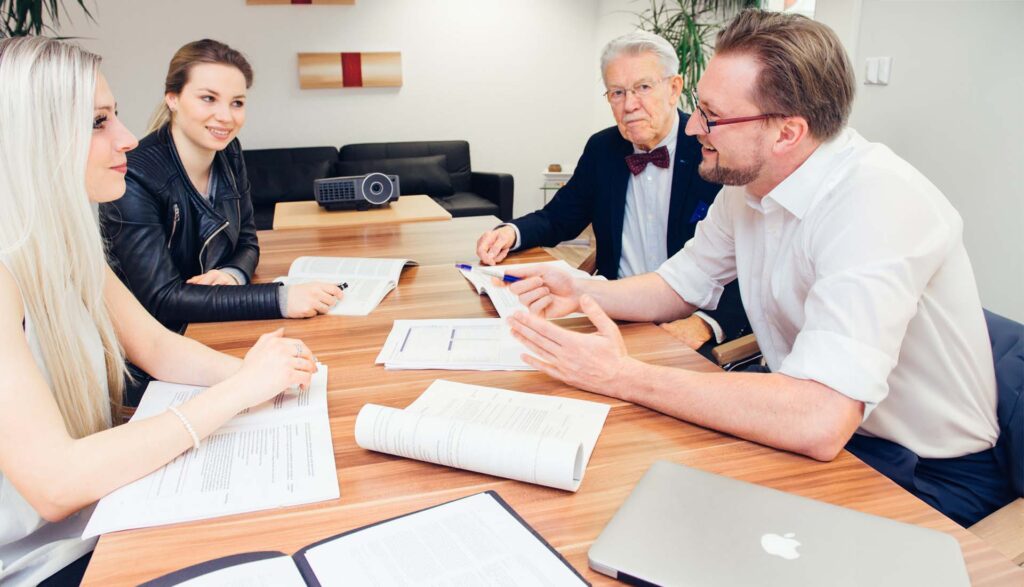 Vier Personen sitzen bei einer Besprechung zusammen und sprechen über Themen rund um Existenzgründung und Unternehmensberatung
