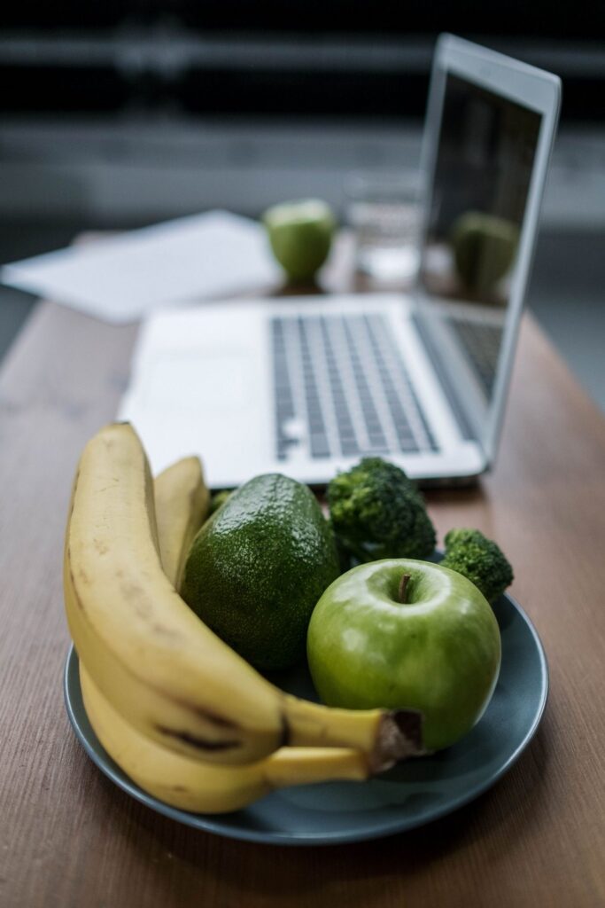 Teller mit Obst und Gemuese vor einem aufgeklappten Laptop
