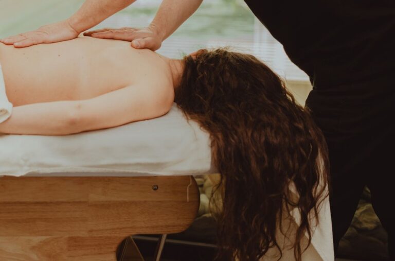 Hände eines Masseurs bei einer Rückenmassage an der Behandlungsliege