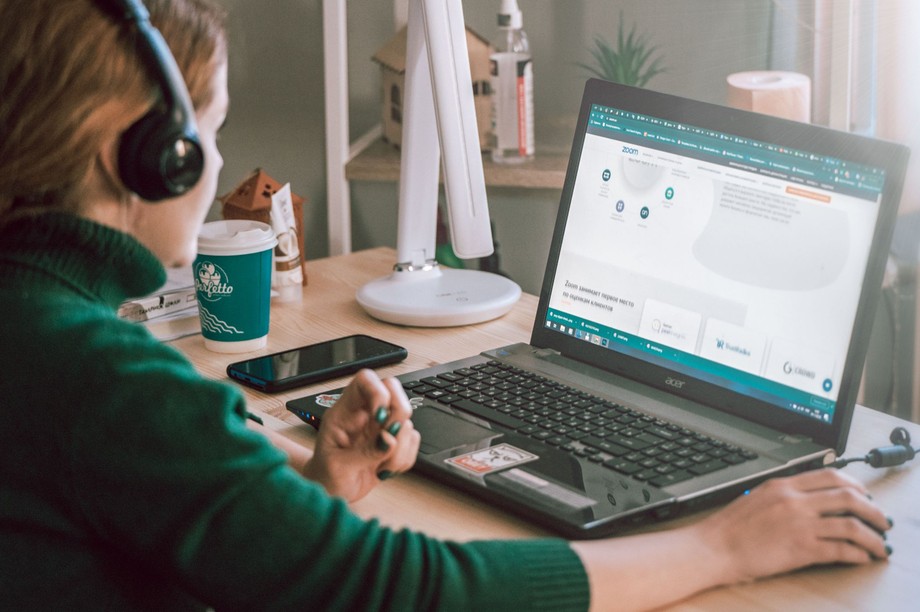 Virtuelle Assistentin mit Kopfhörern arbeitet am Schreibtisch mit Laptop und Notizen