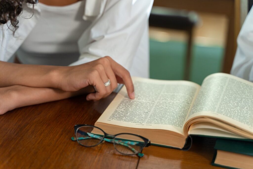 Aufgeschlagenes Nachschlagewerk und Brille auf dem Schreibtisch