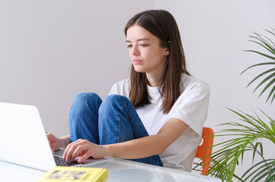 Übersetzerin arbeitet am Laptop, daneben liegt ein Buch